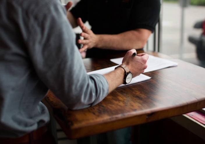 Two people discussing plans across a wooden table